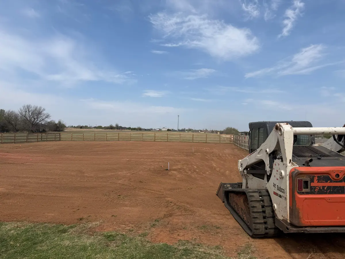 Skid steer parked at the edge of a laser flat arena pad we graded