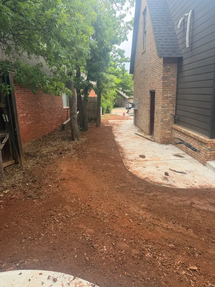 Regraded side yard running between two brick homes under mature trees