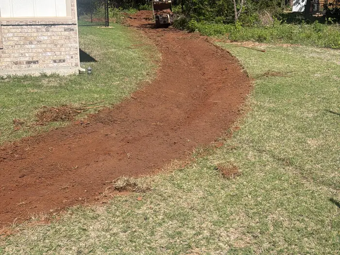 Drainage swale cut curving through a lawn with a compact roller at the far end